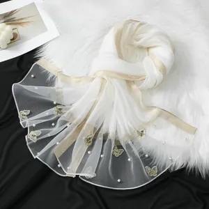 Détail rapproché d'une écharpe en organza blanc avec broderie papillon et perles