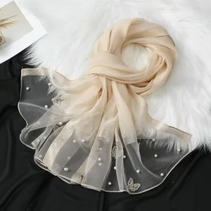 Gros plan d'une écharpe élégante en organza champagne avec broderies papillon et perles