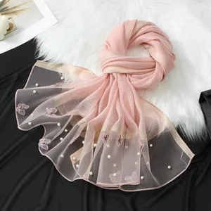 Gros plan d'une écharpe élégante en organza rose avec papillons brodés et petites perles