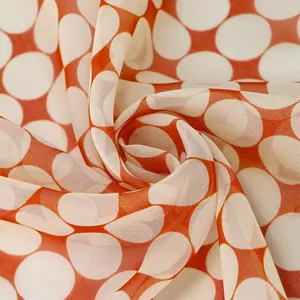 Macro view showing the soft texture of orange chiffon fabric with white polka dots