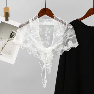 Detailansicht eines weißen bestickten Spitzen-Dreieckstuchs mit floralem Muster.