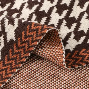 Gros plan sur la texture du tissu en maille pied-de-poule marron et blanc de qualité.