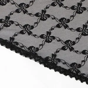Nahaufnahme von schwarzem Spitzenstoff mit komplizierten Blumen- und Schleifenstickereien.