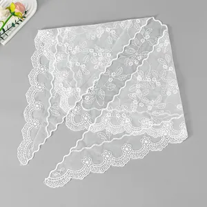 Detailansicht eines weißen Spitzen-Dreieckstuchs mit floraler Stickerei und Wellenrand