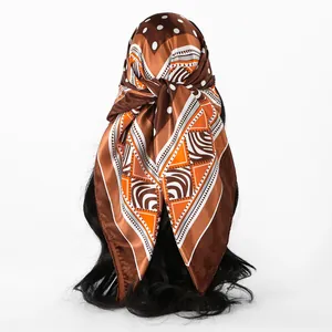 Detailed view of brown satin square headscarf with white polka dots and geometric patterns.