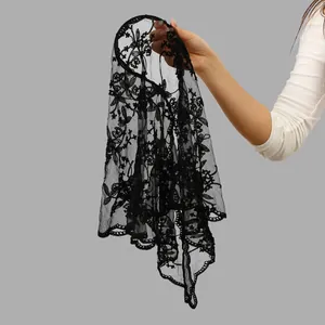 Close-up detail of black lace triangle scarf with delicate floral embroidery.