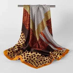 Détail d'un foulard carré en satin soyeux avec imprimé léopard et motifs de design géométriques.
