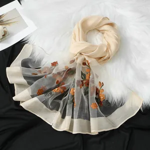 Dettaglio di un elegante foulard in organza beige ricamato con motivi floreali