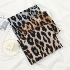 Vista detallada de bufandas con estampado de leopardo en tonos gris, marrón y crema.
