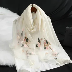 Vista dettagliata di una sciarpa leggera in organza crema con ricami floreali squisiti