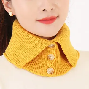 Vista detallada de un calentador de cuello de punto amarillo con tres botones.