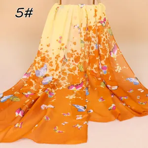 Detailweergave van chiffon sjaal met vlinderprint en oranje kleurverloop effect