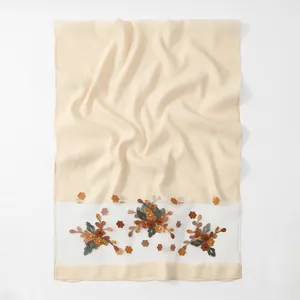 Vista dettagliata dell'elegante ricamo floreale su una sciarpa in organza beige