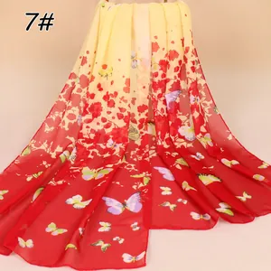 Detailopname van een lichte chiffon sjaal met rode en gele vlinder- en bloemenprint