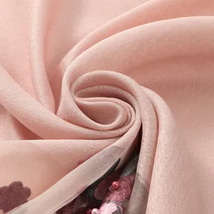 Dettaglio ravvicinato di una sciarpa in organza rosa con ricami floreali e perle