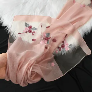 Vista dettagliata di una sciarpa in organza rosa con un elegante ricamo floreale di begonia