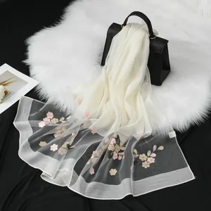 Elegante scialle in organza bianca con ricamo floreale su sfondo di pelliccia sintetica.