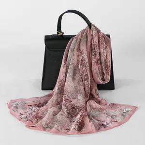 Elegant pink floral georgette long scarf for women draped over a black leather handbag