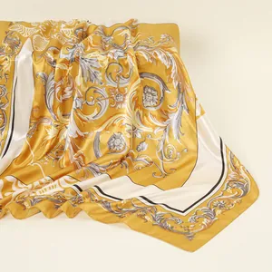 Nahaufnahme eines quadratischen Schals mit goldenem Barockmuster und elegantem Seidenglanz