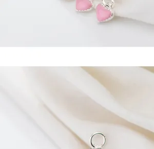 Dettaglio di ciondoli a cuore in smalto rosa e nero in argento S925 su tessuto bianco
