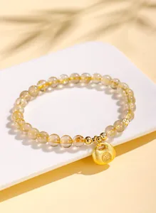 Nahaufnahme eines goldfarbenen Rutilquarz-Armbands mit traditionellem Schloss-Anhänger