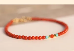 Close-up of a delicate natural red agate bracelet with turquoise and gold beads details