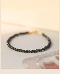 Nahaufnahme eines 3-mm-Obsidian-Armbands mit facettierten Perlen und Goldverschluss
