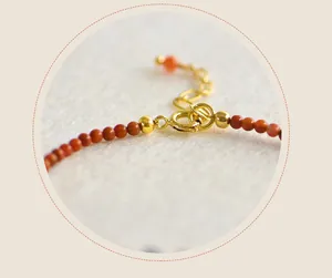 Dettaglio ravvicinato della chiusura dorata e delle perle di agata rossa di un bracciale