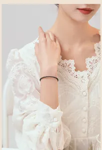 Detail eines 3mm Obsidian-Perlenarmbands am Handgelenk einer Frau mit Spitzenkleid