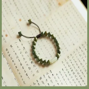 Gros plan d'un bracelet en bois de santal vert avec capsule en jade Hetian et cordon
