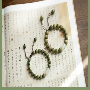 Détail de bracelets en bois de santal vert avec tube de jade sur un livre ancien