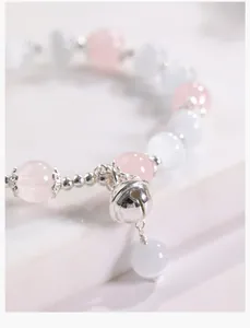 Primer plano de pulsera de cuarzo rosa natural con colgante de cascabel