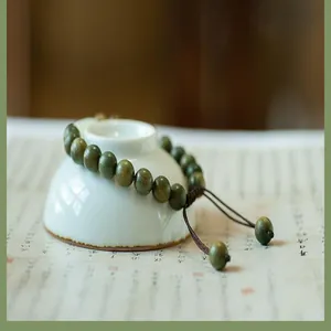 Détail d'un bracelet artisanal en perles de bois de santal vert avec cordon réglable