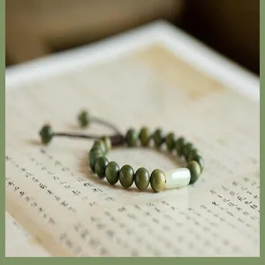 Détail macro de perles en bois de santal vert et capsule de jade blanc sur cordon