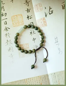 Détail d'un bracelet en perles de bois de santal vert avec jade néphrite sur calligraphie