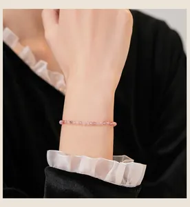 Nahaufnahme eines 3 mm großen Erdbeerkristall-Armbands am Handgelenk einer Frau