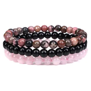 Detailed macro shot of triple stacked natural stone bracelets with rose quartz beads.