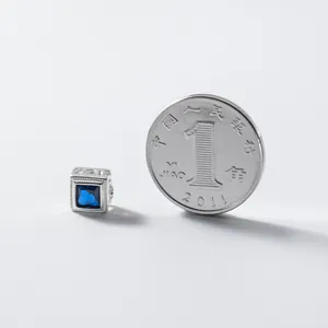 Cuenta cuadrada de plata 925 de 6 mm con piedra azul junto a moneda para escala