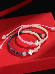 Gros plan de deux bracelets trèfles en argent 925 sur une boîte cadeau rouge élégante.