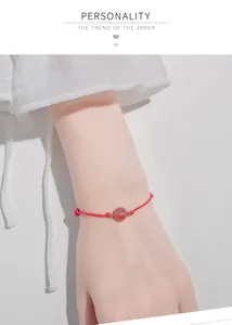 Minimalist handmade red string bracelet with strawberry crystal bead on a female wrist