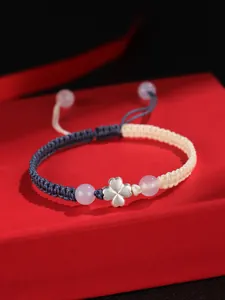 Gros plan d'un bracelet tissé à la main avec trèfle à quatre feuilles en argent 925 et agate