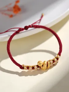 Détail d'un bracelet tressé rouge fait main avec un charme de serpent doré pour femme.