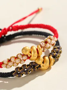Détail macro du bracelet en cordon tressé à la main avec breloque serpent dorée
