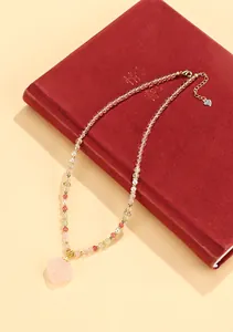 Close-up of a New Chinese style beaded necklace with a pink crystal pendant on a red book