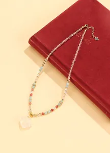 Elegant beaded necklace with carved white crystal pendant on a red vintage book