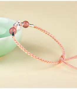 Nahaufnahme des aufwendigen Drachenanhängers aus S999 Silber an einem roten Armband