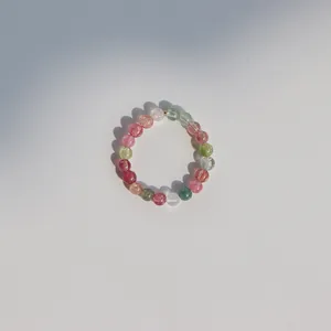 Macro view of a delicate 3mm natural rainbow tourmaline beaded ring with sunlight shadow