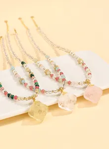 Detail showing trio of beaded necklaces with carved crystal pendants on white plate