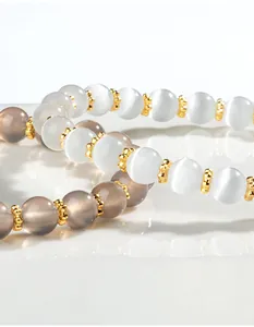 Macro-opname van dichtbij die de textuur toont van kattenoog en grijze kralenarmbanden met goud