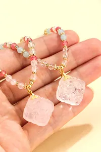 Detailed view of hand-carved crystal flower pendant on multi-gemstone beaded necklace